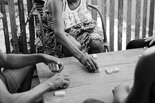 Black and white photo of people playing dominoes on a wooden table in Brazil.
